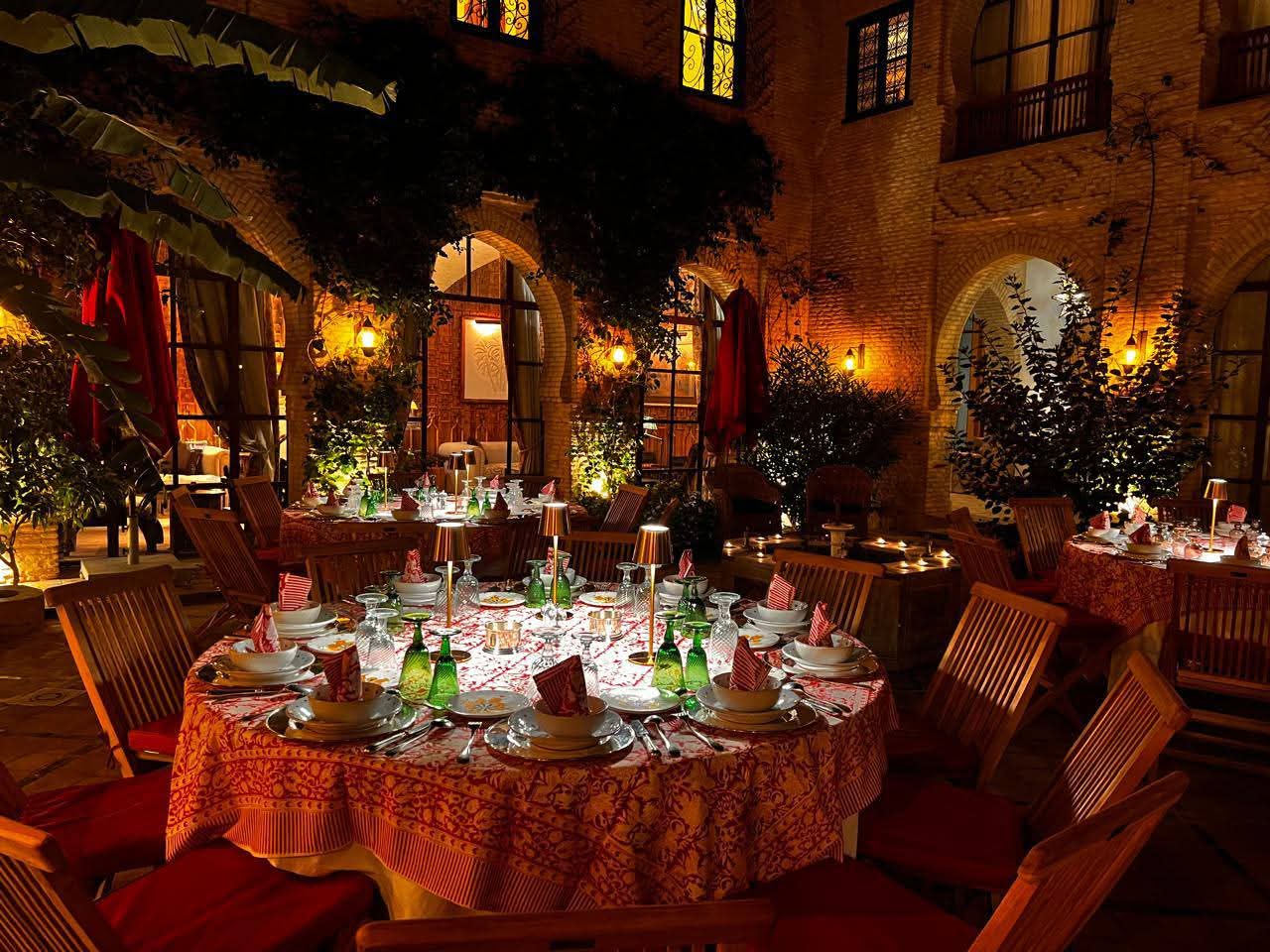 Tables rondes dressées sous les arcades illuminées